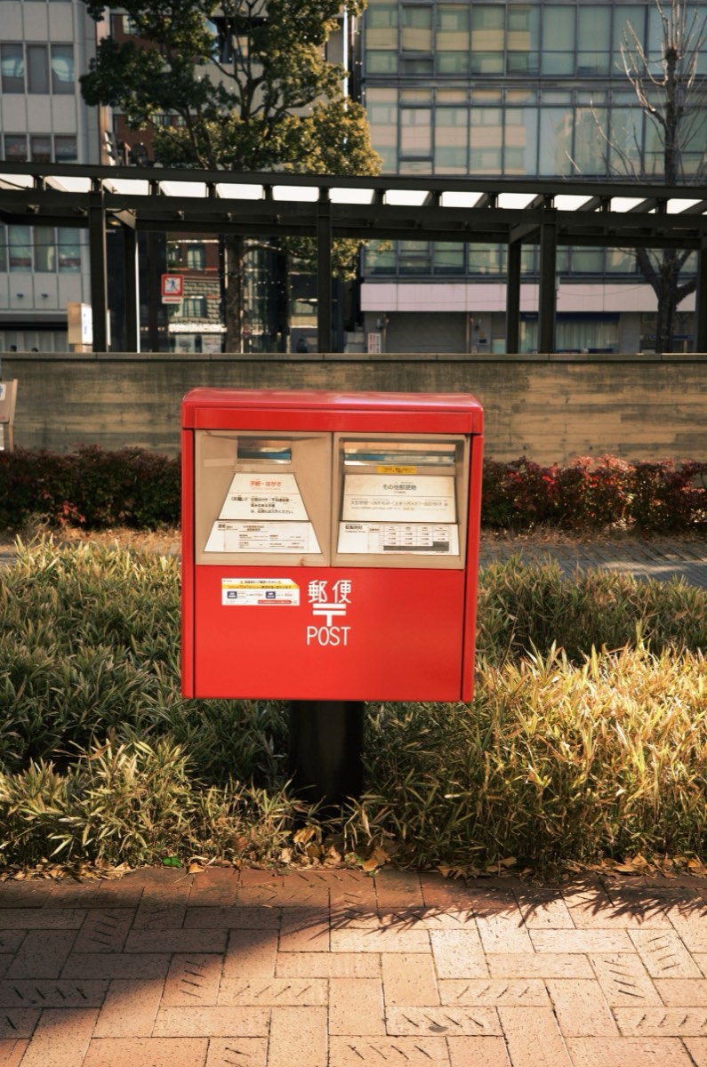 A red Japan Post street mailbox in a Japanese city